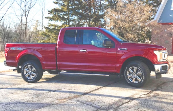 Red Ford F-150 parked outside a home, How Big a Travel Trailer Can an F-150 Pull? [Towing Capacity]