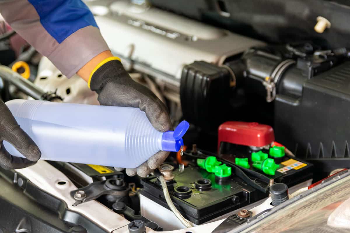 he mechanic adds distilled water and check the car battery