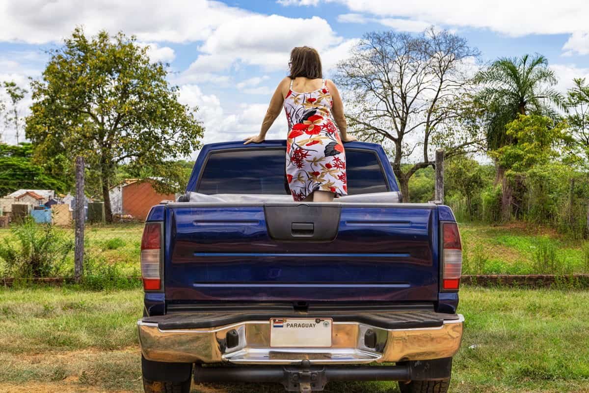A woman stands on the back of a pick-up truck