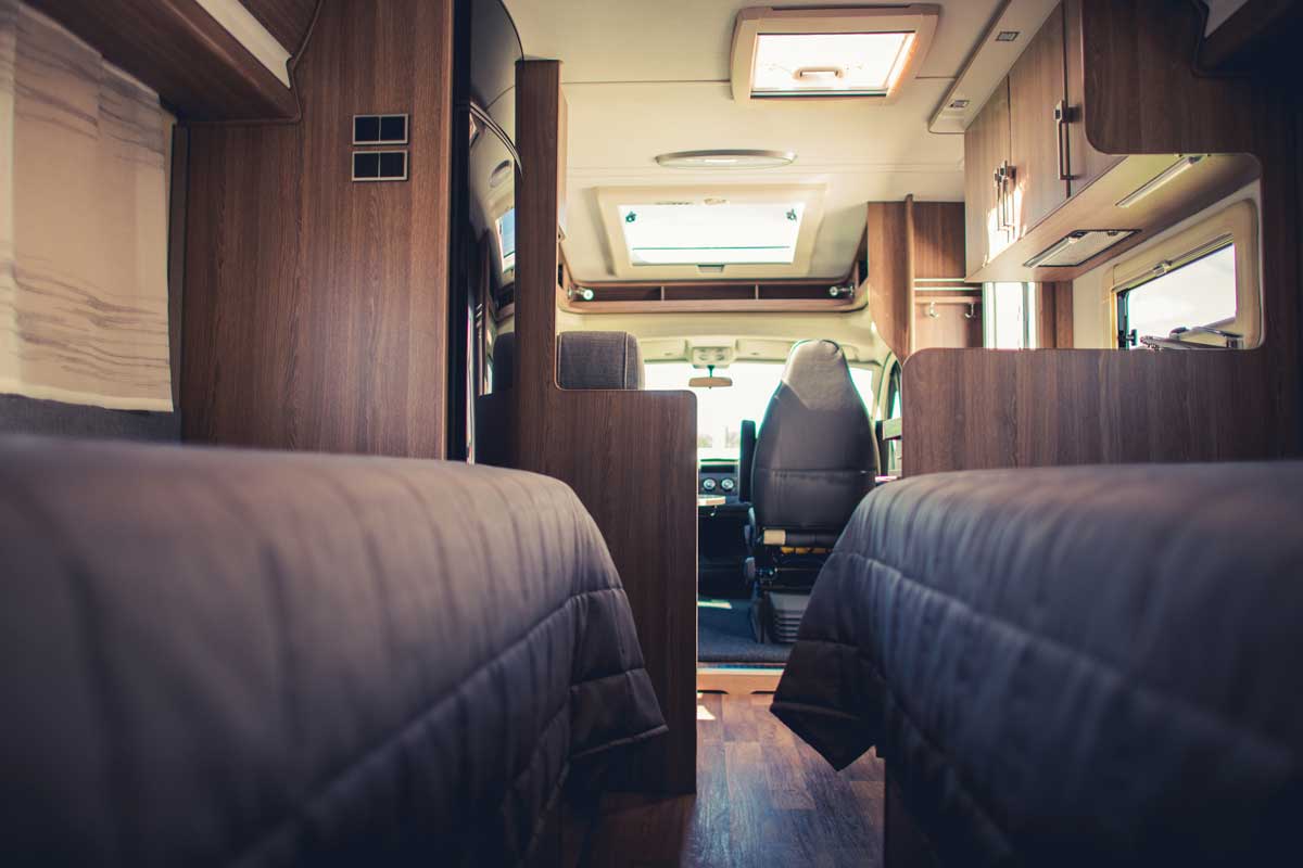 Interior of an RV with gray sofas and other mobile furniture's while moving on the road, 21 Tips for Properly Storing Stuff in Your RV When on the Road