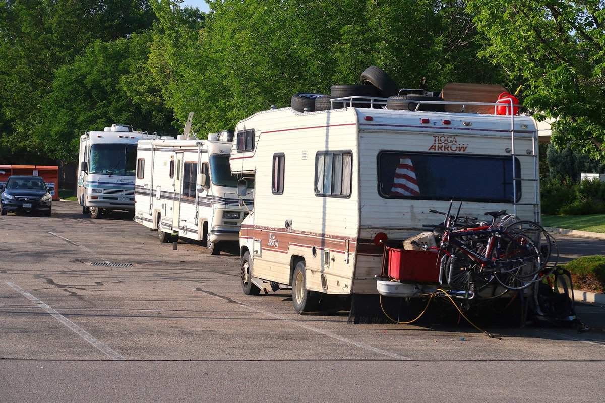 Many campers and RVs park in a public shopping center parking lot. Living out of your camper. Nomad life. Squatting in the parking lot.