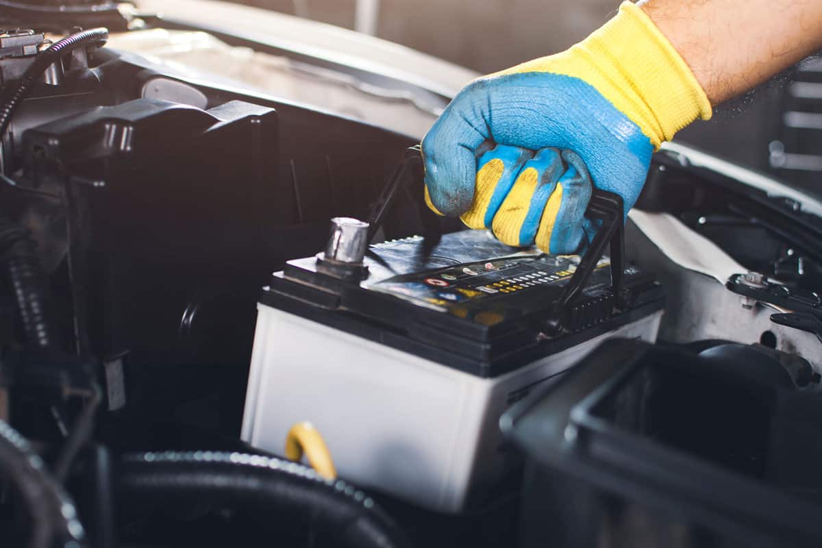 technician pulling car old battery replacement