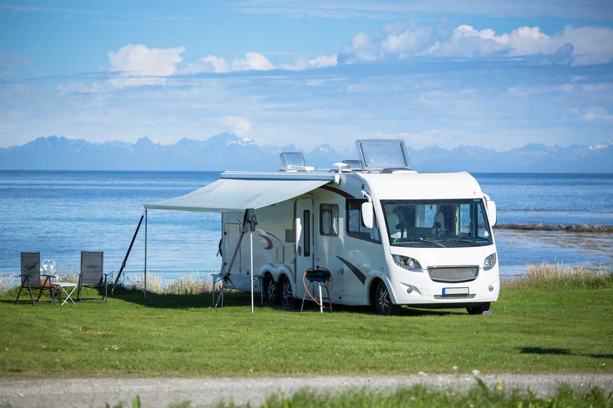 Parked RV near the ocean with an open awning, RV Awning Stuck: What To Do? featured image