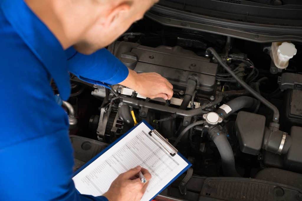 Car mechanic going over checklist for inspecting