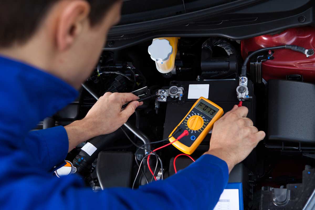 Mechanic checking battery using battery checking equipment