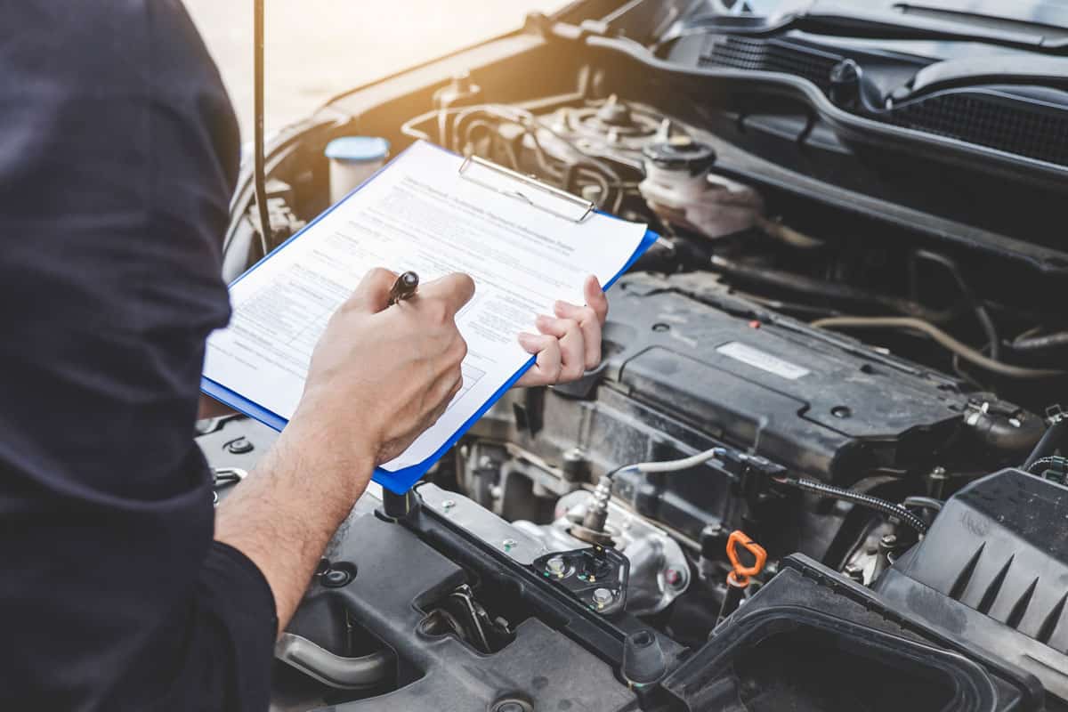 Services car engine machine concept, Automobile mechanic repairman checking a car engine with inspecting writing to the clipboard the checklist for repair machine