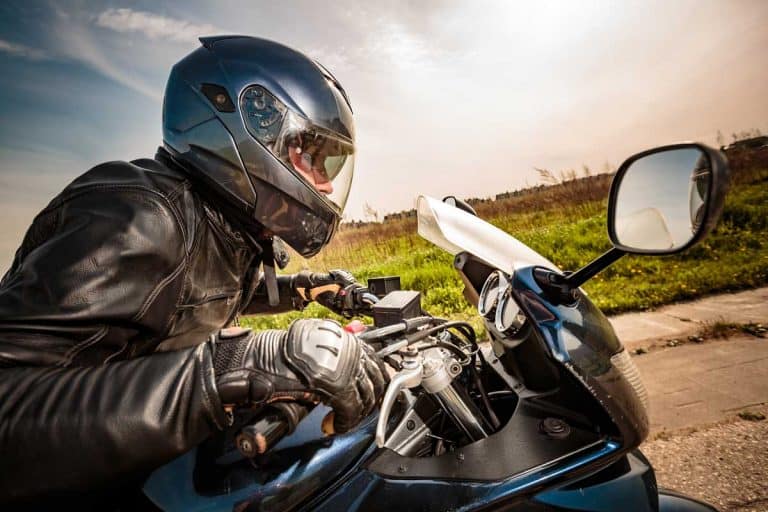 Motorcycle rider with helmet and jacket ducking down and revving up to accelerate, Where To Buy Motorcycle Gear [Top 40 online stores]