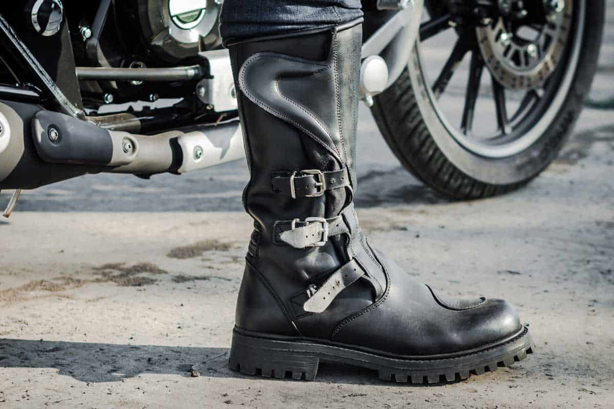 Biker leg in a boot against the backdrop of a motorcycle