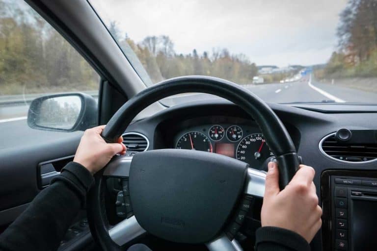 Woman with black sleeves driving on the highway, Steering Wheel Not Straight While Driving [Here's What To Do]