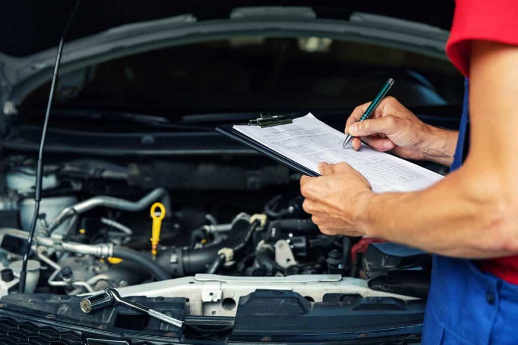 Car maintenance and repair mechanic writing checklist paper