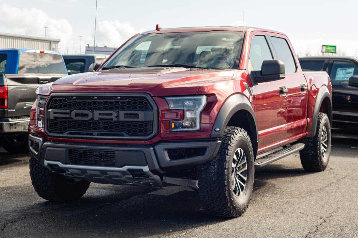 2020 Red Ford F-150 Raptor pickup truck at a Ford dealership.