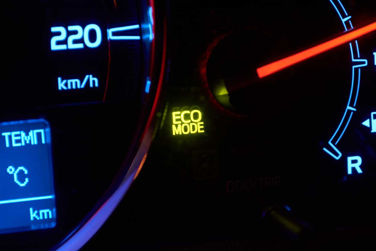 Close up of car dashboard with green hybrid mode icon on