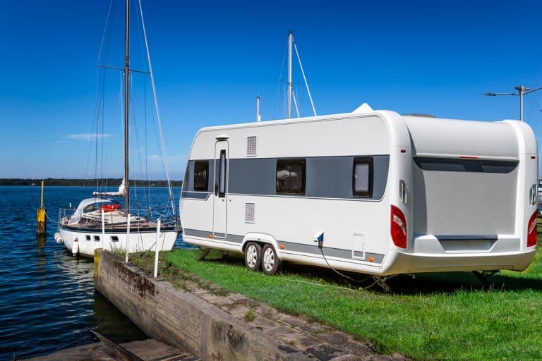 A 30' trailer parked on a dock with a sailboat up front, How Much Does a 30' Travel Trailer Weigh?