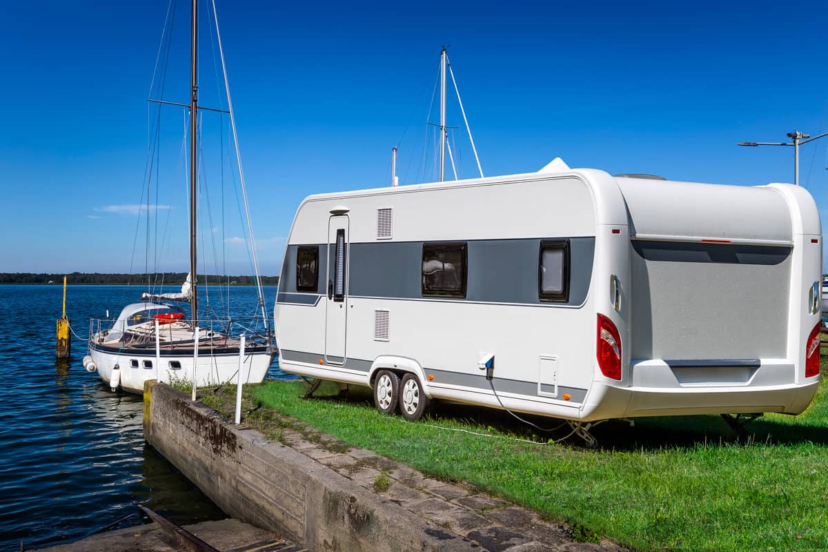 A 30' trailer parked on a dock with a sailboat up front, How Much Does a 30' Travel Trailer Weigh?