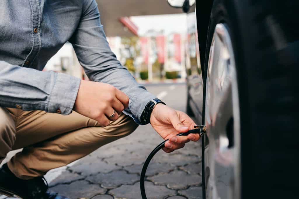 A man checking the tire pressure of his car