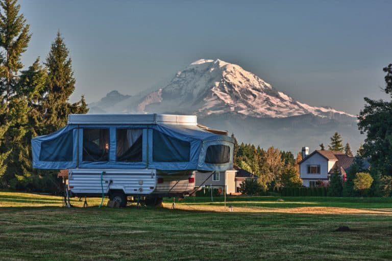 A pop-up camper already set up for camping at a camp site with a panoramic view of Mount Rainier, Do Pop Up Campers Have Bathrooms? [3 Bathroom Types Discussed]