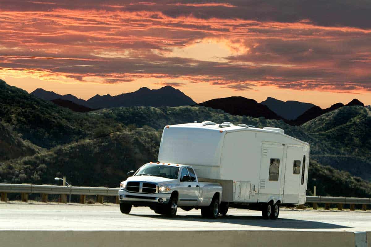 A truck pulling a 5th wheel with a beautiful sunset in the background, What Can My Truck Tow? [Inc. Specs for Popular Models]