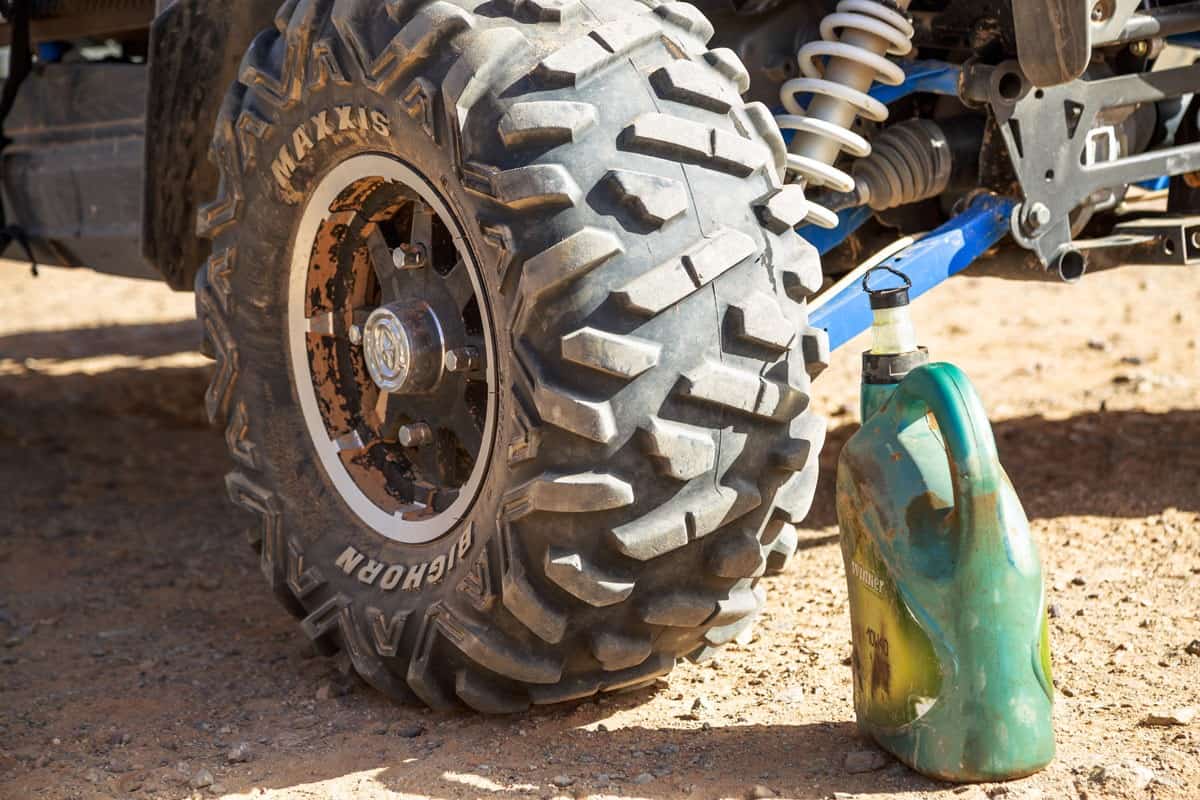 ATV quad wheel and oil can used for lubricating quad bike at desert repair station at Merzouga