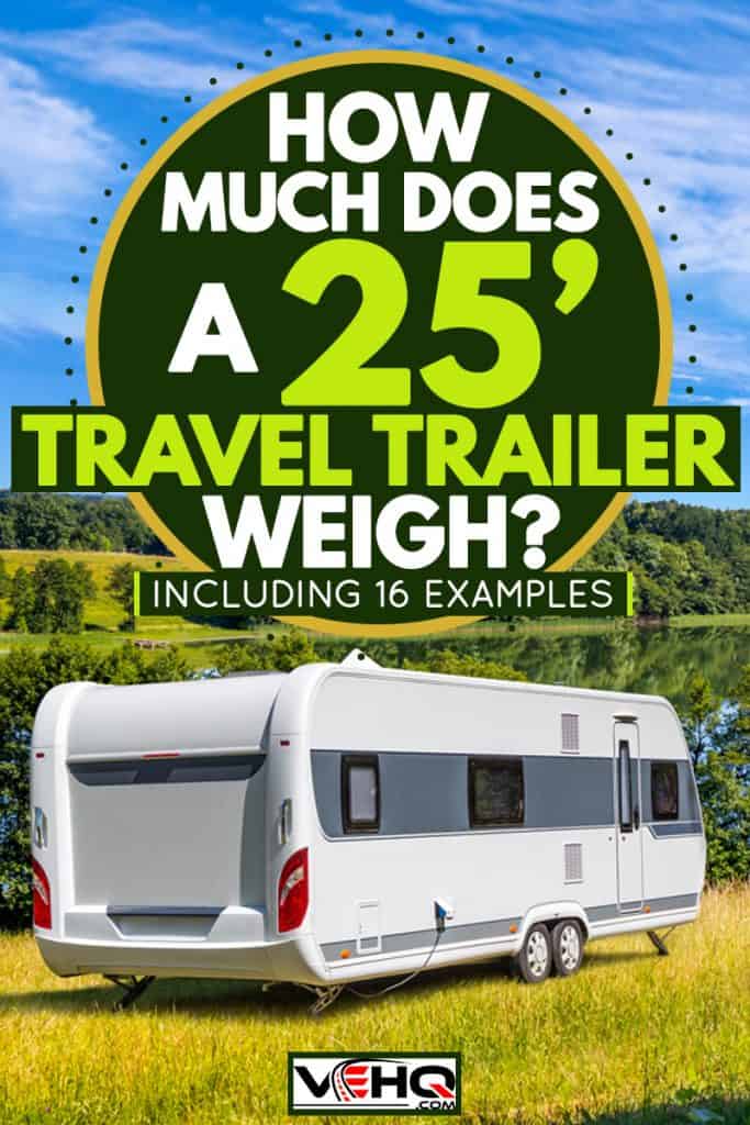A travel trailer parked on a grassy field with an overview of a lake, How Much Does A 25′ Travel Trailer Weigh? [Inc. 16 examples]