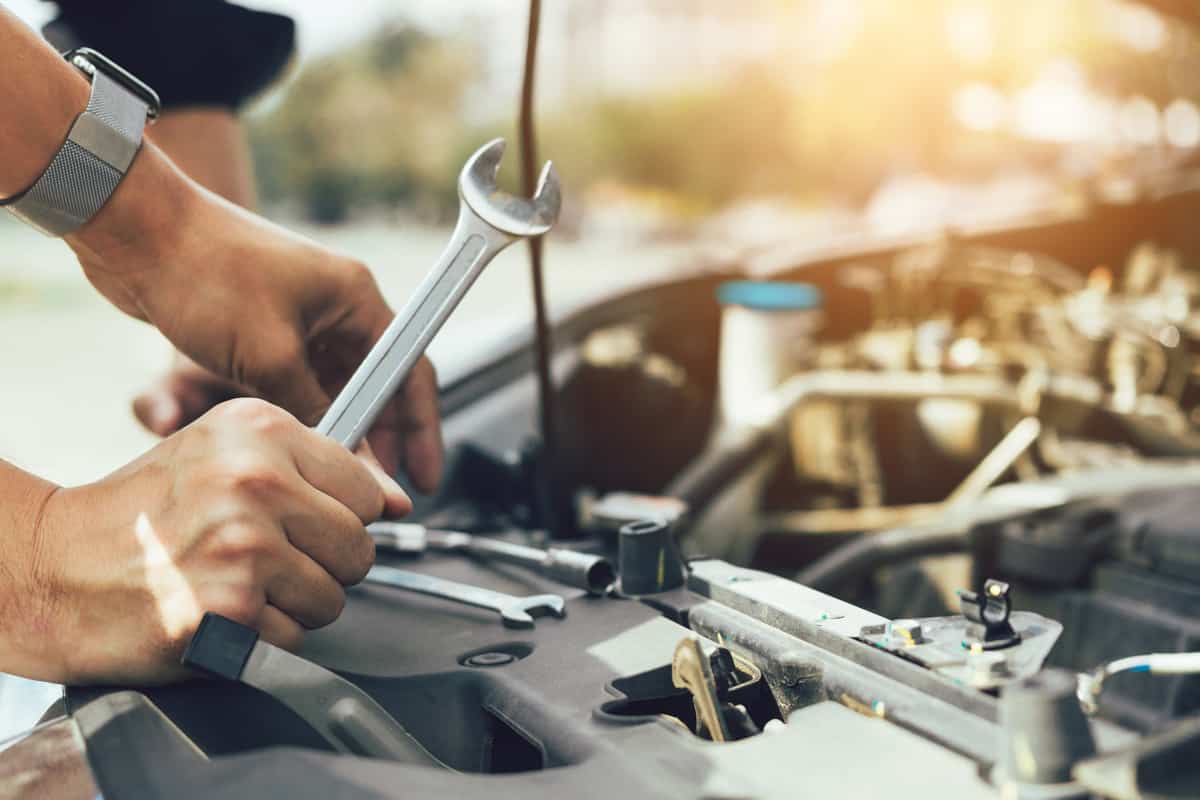 A mechanic holding a wrench and checking the engine for any repairs and in need of maintenance, How Much Does A Car Engine Cost To Replace?