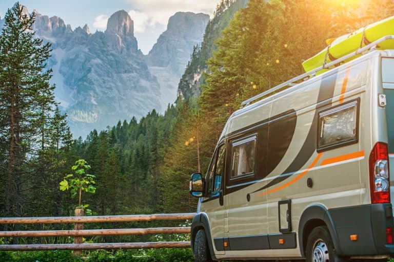 A motorhome parked on a parking lot with a panoramic view of the wild mountains and beautiful skies, What Is The Shortest Class B Motorhome?