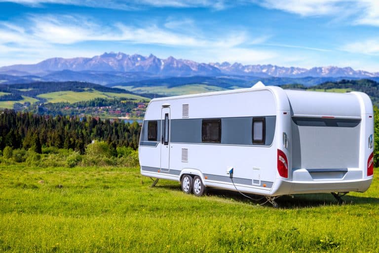 An Artic Fox RV parked on a hill with a panoramic view of a town surrounded by mountain ranges and blue skies, Arctic Fox North Fork Travel Trailer Floor Plans & Features Guide