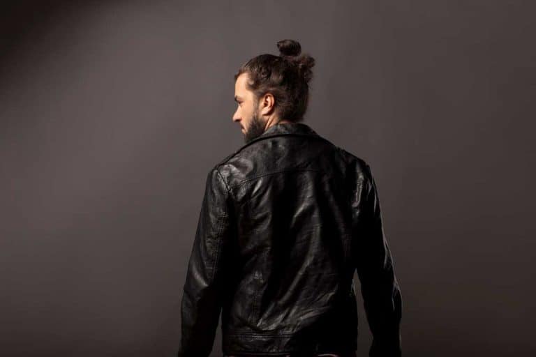 back view of man with beard and bun in black leather jacket, How To Wear Your Hair When Riding A Motorcycle?