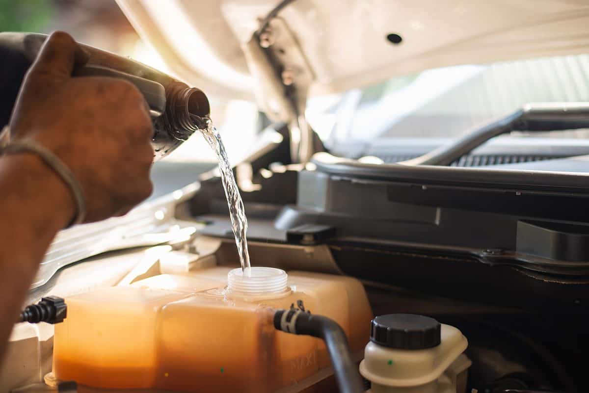 A hand filling car cooling service in engine system with water coolant