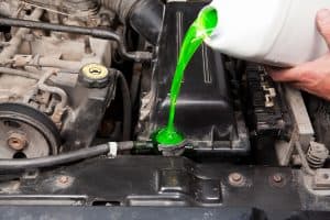 A mechanic pouring engine coolant into the engine, Is Engine Coolant Flammable? [Inc. Safe Handling Tips]