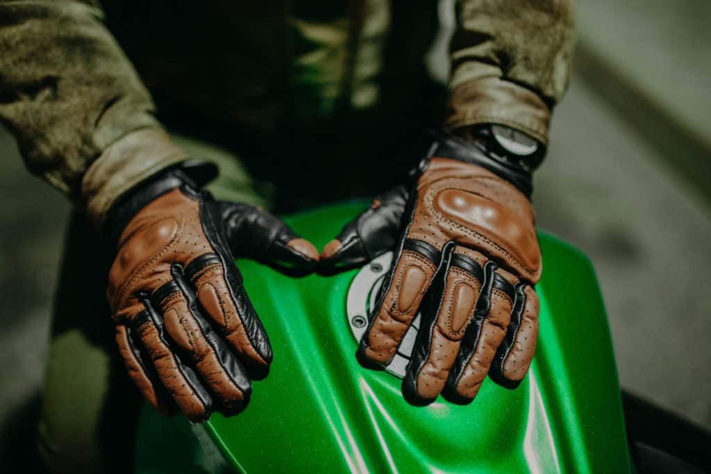 A motorcycle driver wearing brown leather gloves