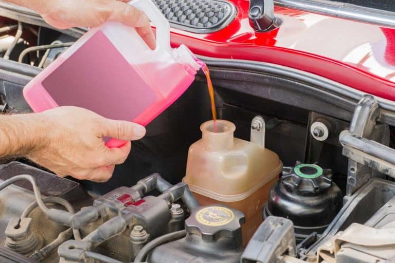 A person pouring car coolant in a car engine, How to Add Antifreeze To Your Vehicle [6 Crucial Steps]