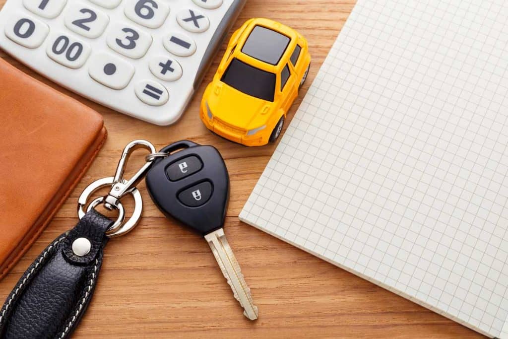 Car key with notebook calculator and pocket money on wood table, Are Car Keys Magnetic? [Here's What They're Made Of]