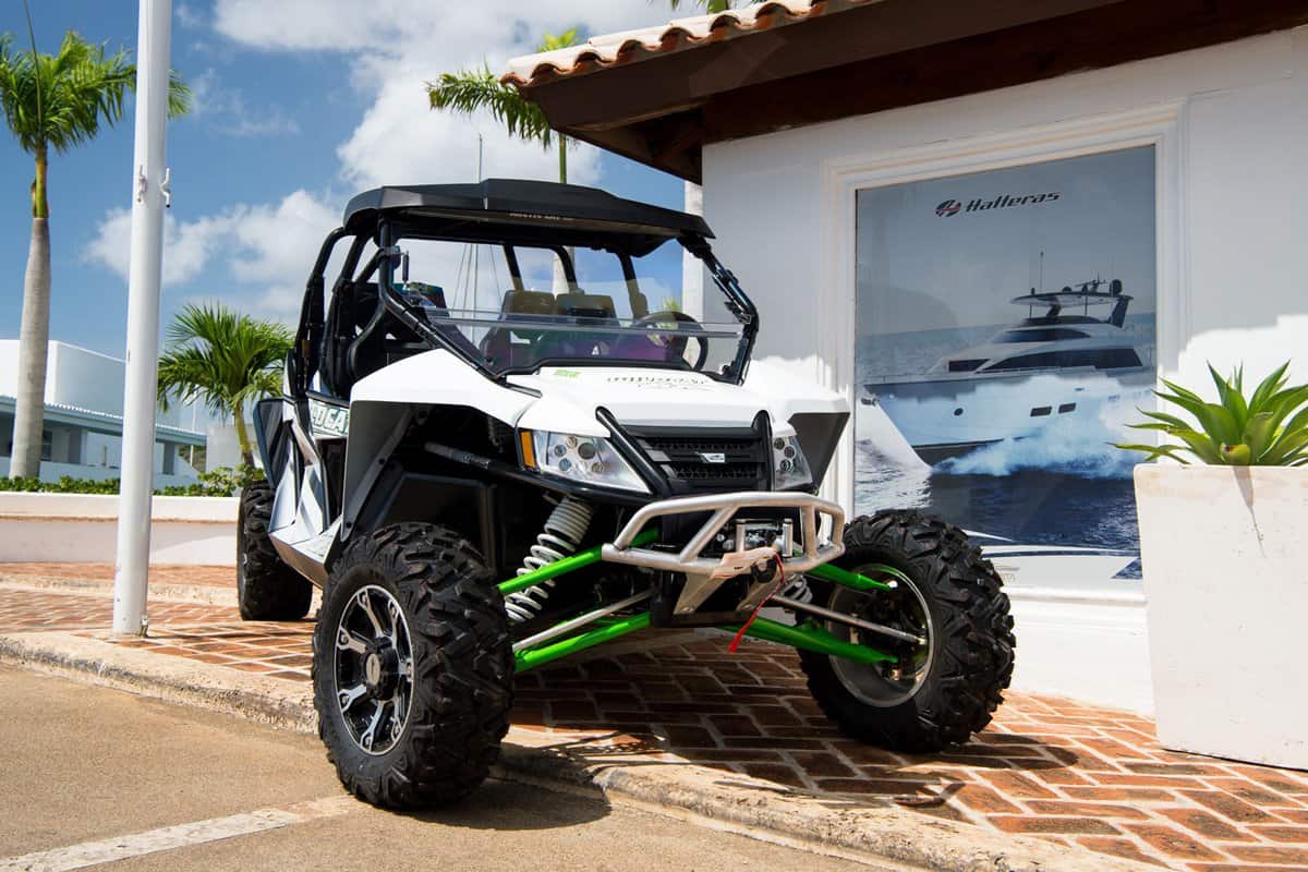 big cool sport open car of arctic cat brand with wheels and hull white and green color parking sunny day outdoor near building