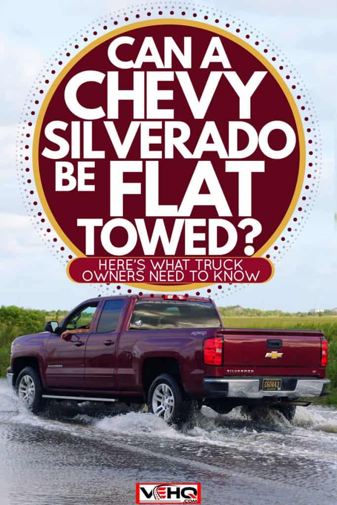A red Chevrolet Silverado moving on a flooded road, Can a Chevy Silverado Be Flat Towed? Here's What Truck Owners Need to Know