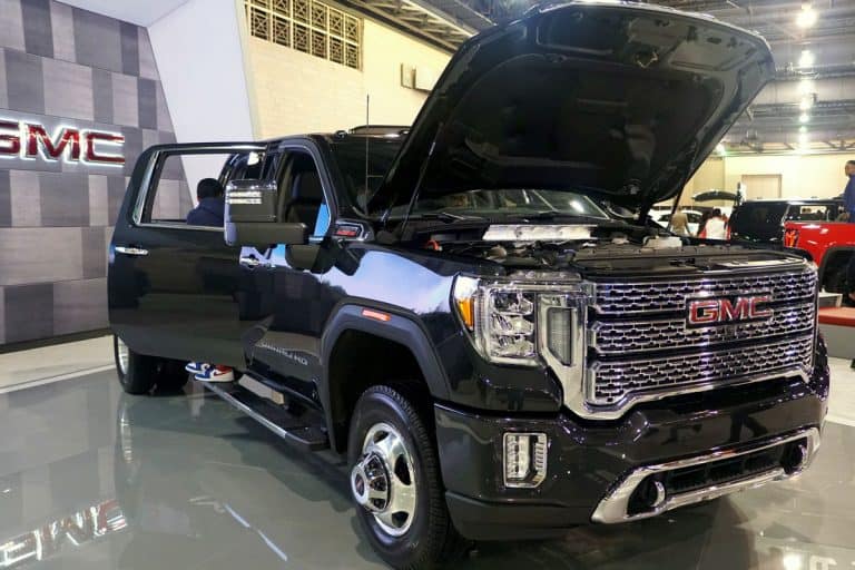 Huge dual rear GMC Sierra 3500 HD with an opened hood and doors displayed at a car show, Can A GMC Sierra Pull A Travel Trailer?