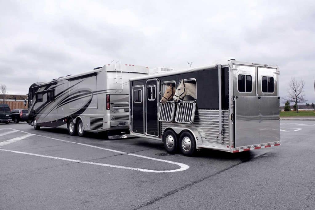 A large motorhome and horse trailer in parking lot