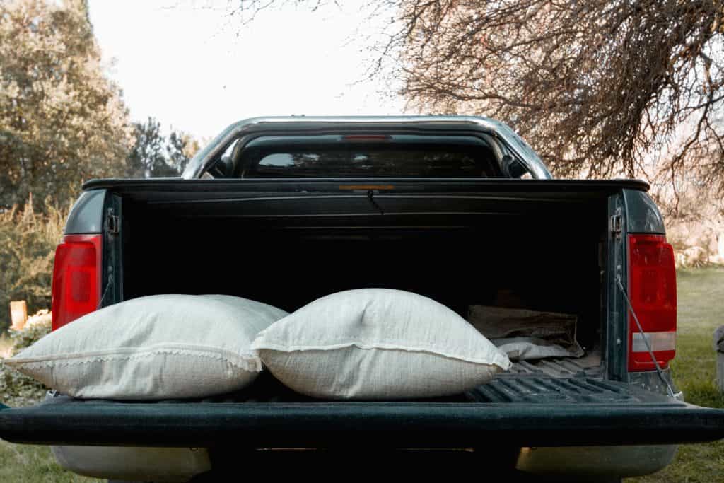 An open truck bed with two sacks of sand on the back