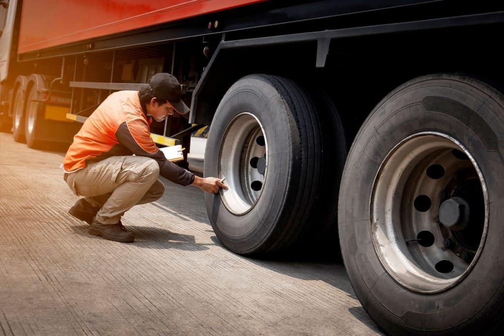Truck driver inspecting safety daily check a truck wheels
