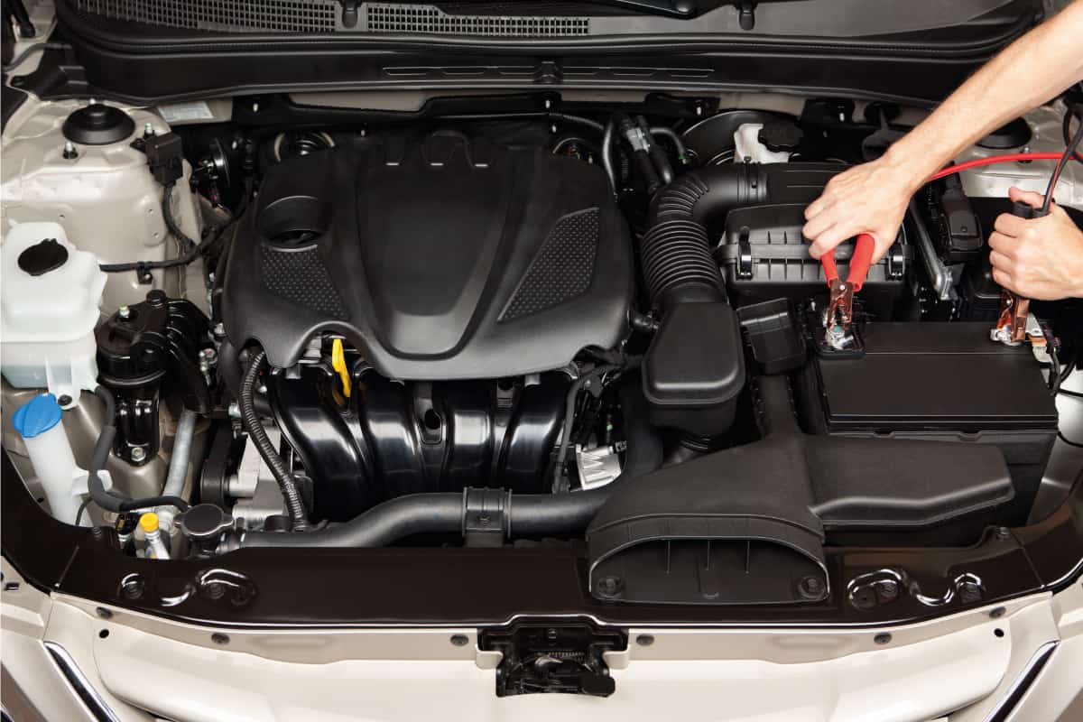 Car mechanic using jumper cables on a car battery in the engine bay of a car, How Much Does A Car Battery Weigh?