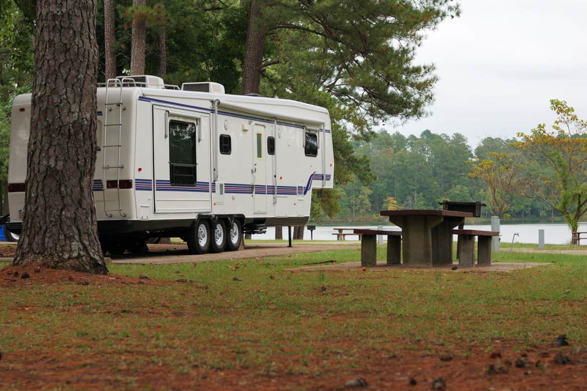 A fifth wheel parked on the camping ground of a nature park with a scenic view of a lake, Best Two-Bedroom Fifth Wheels