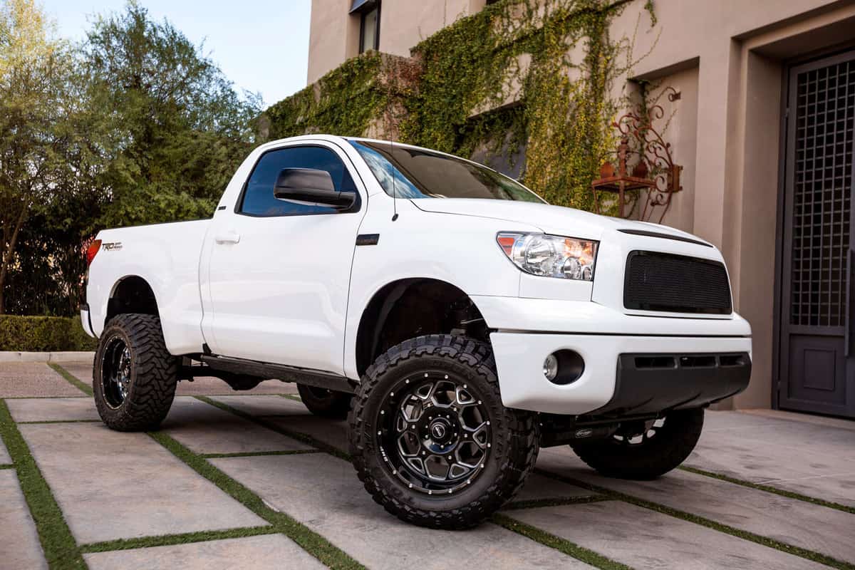An old version of a Toyota Tundra parked outside a mansion