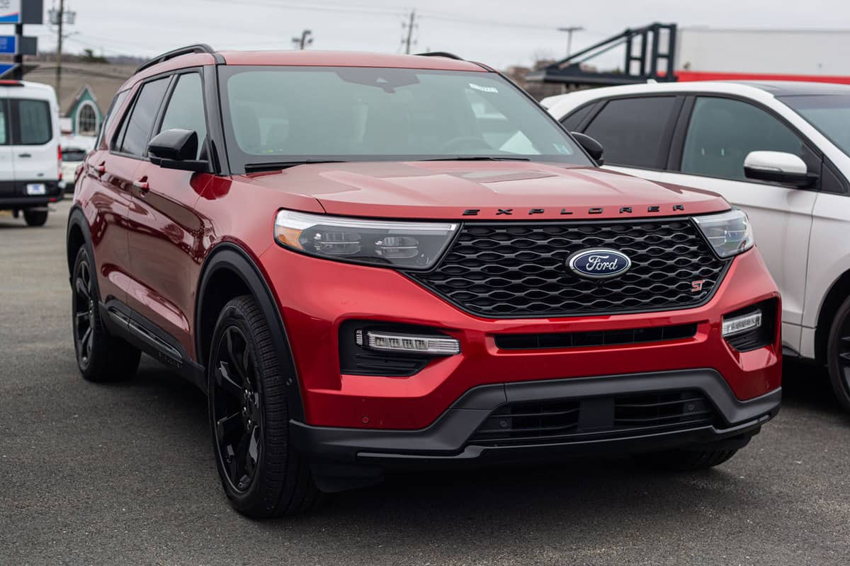 A luxurious red colored Ford Explorer parked outside a parking lot