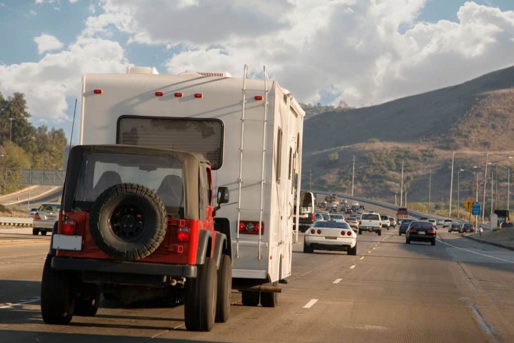 An rv towing a red jeep