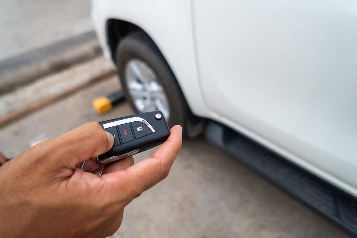 Hand pressing the button on the remote to lock or unlock the car with the remote control, How To Remote Start Hyundai Palisade