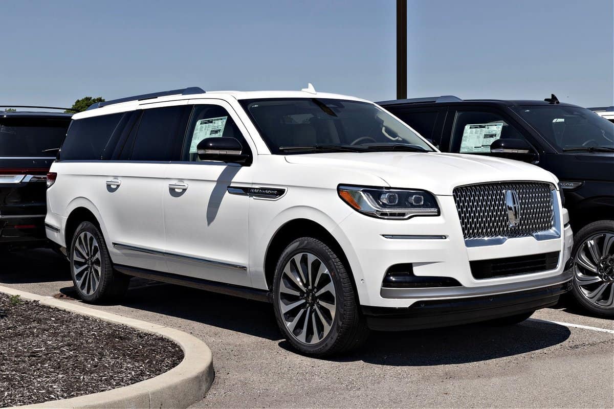 White 2023 Lincoln Navigator luxury full-size SUV on display inside a dealership showroom in Fishers, Indiana in May 2023. The SUV is the Reserve trim level featuring 22-inch polished aluminum wheels, running boards, and chrome accents around the windows.