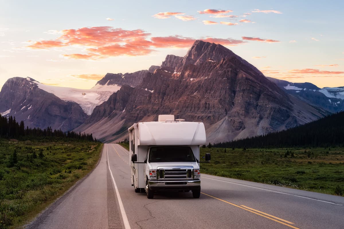A Ford motorhome traveling on a long stretch of highway with a scenic view of the mountains on the background