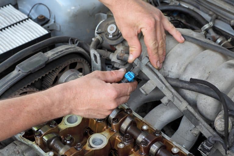 A car mechanic removing the fuel injector of a car, Can Fuel Injector Cleaner Cause Problems?