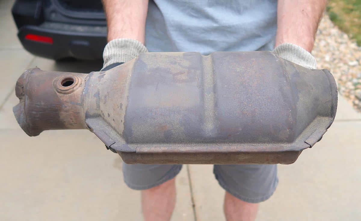 A large and rusty used catalytic converter that is removed from the vehicle