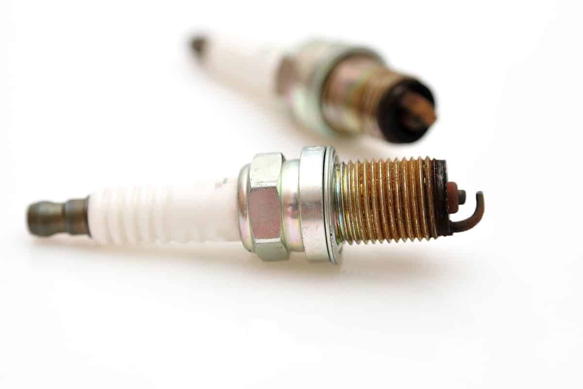 An over used spark plug on a white background