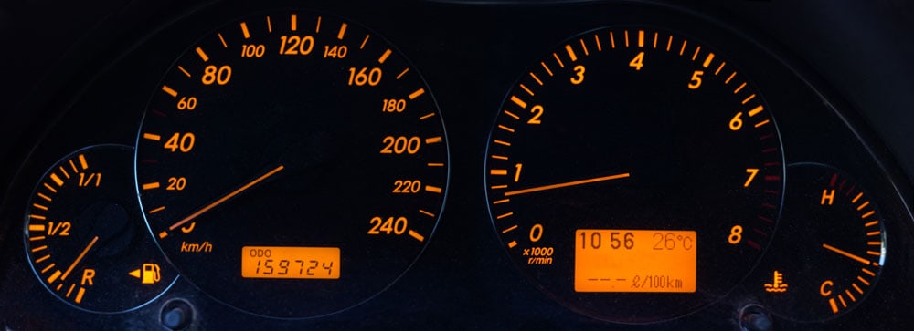 Black car dashboard with yellow backlight of speedometer, tachometer and other instruments of car and engine parameters monitoring, panoramic view close-up